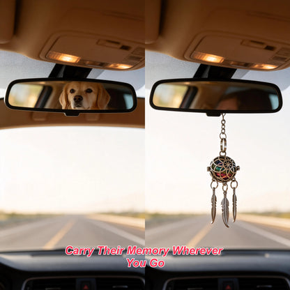 Pet memorial dreamcatcher keychain hanging from a car rearview mirror with a dog in the background