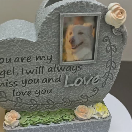 A heart-shaped pet memorial tombstone with floral arrangement