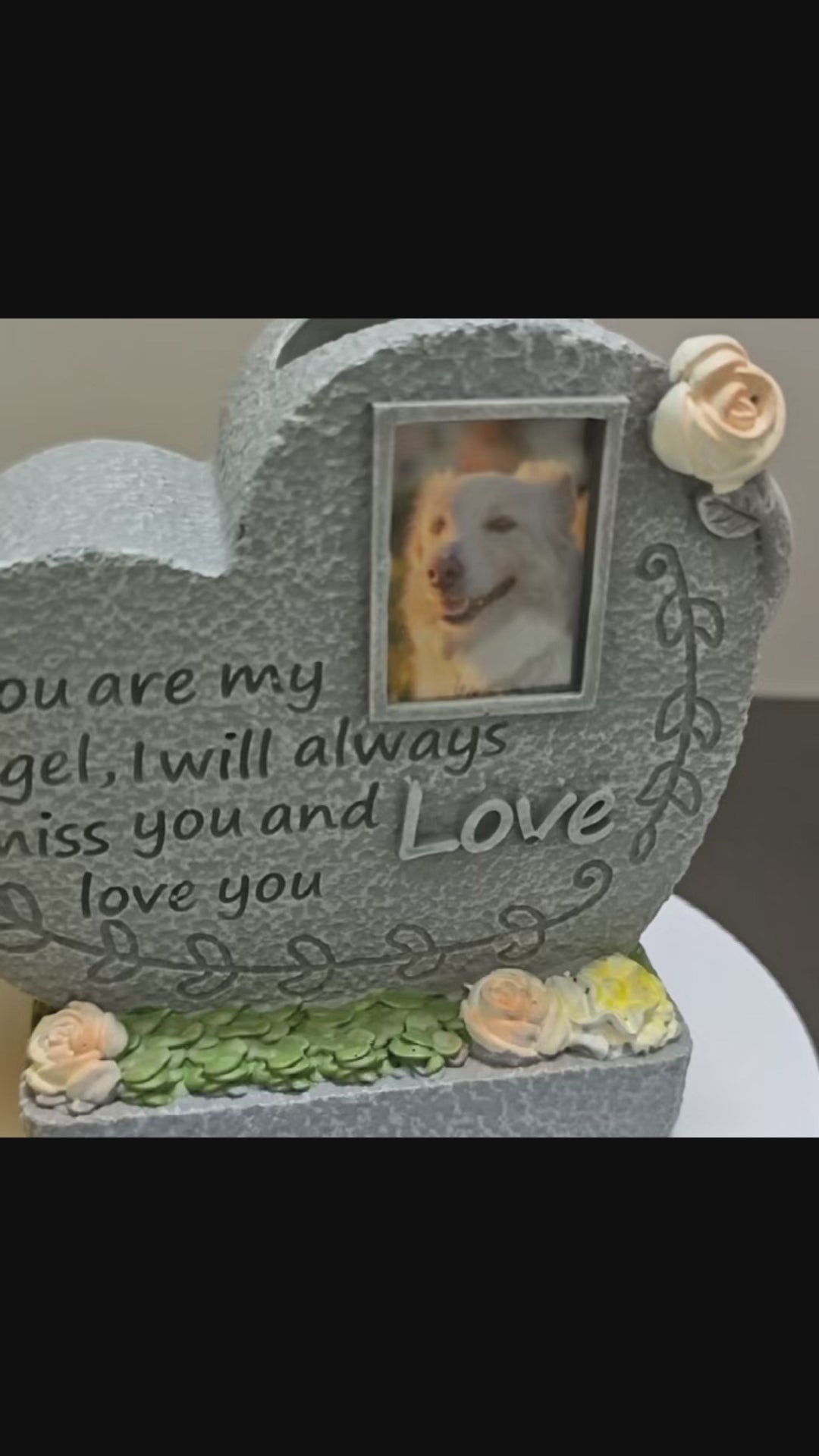 A heart-shaped pet memorial tombstone with floral arrangement